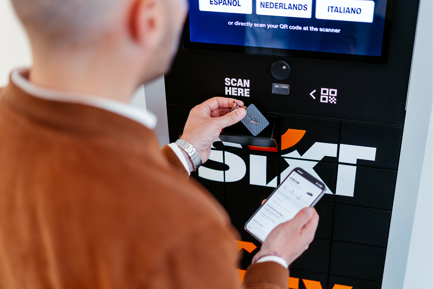 A customer holding a key fob up to the scanner on an illuminated self-service keybox terminal